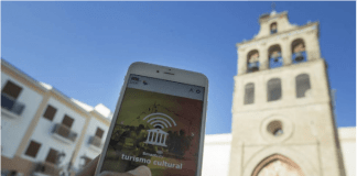Los pueblos también quieren ser ‘inteligentes’ Mano sosteniendo móvil al fondo iglesia